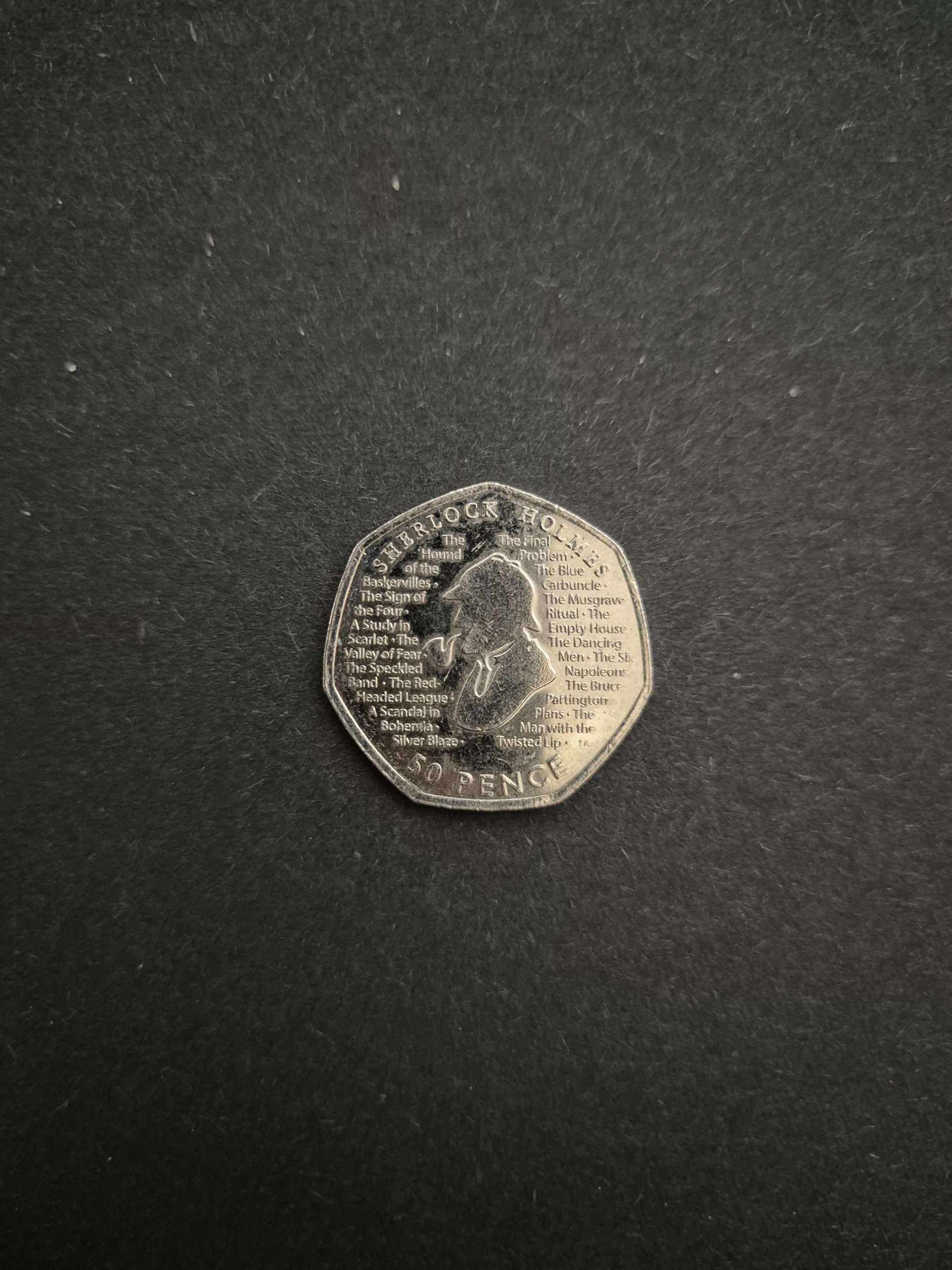 2019 Sherlock Holmes 50p Coin - UK Collector's Item Image of a 2019 UK 50 pence coin featuring Sherlock Holmes and titles of his stories.