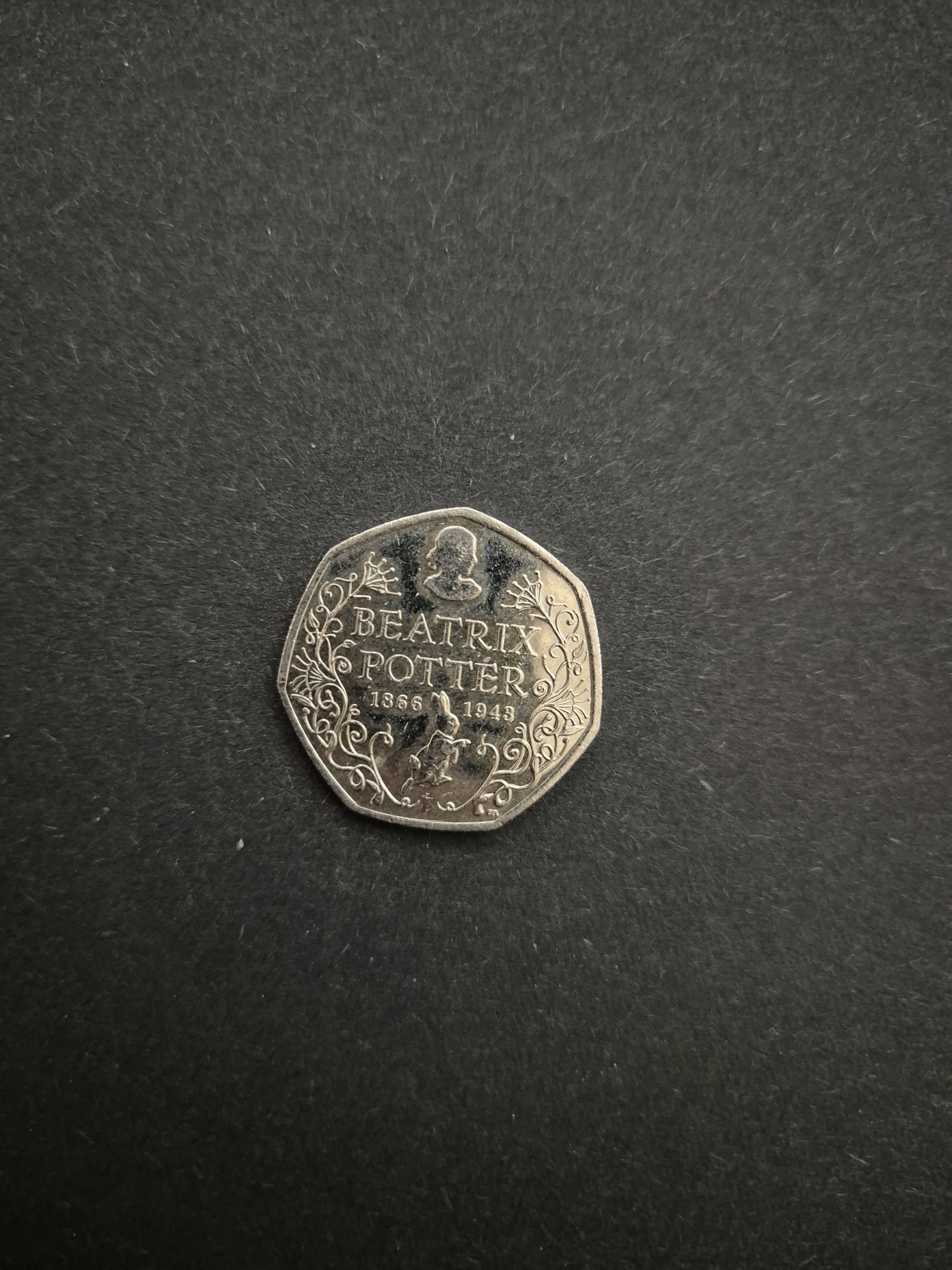 2016 Beatrix Potter 50p Coin - UK Collector's Item Image of a 2016 UK 50 pence coin featuring Beatrix Potter, Peter Rabbit, and floral designs.