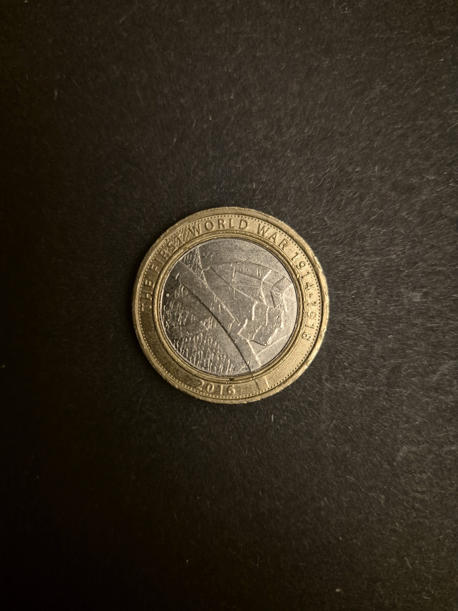 2016 UK £2 Commemorative Coin - First World War Centenary Close-up image of a 2016 British two-pound coin commemorating the centenary of the First World War. The coin features a design depicting trench warfare.